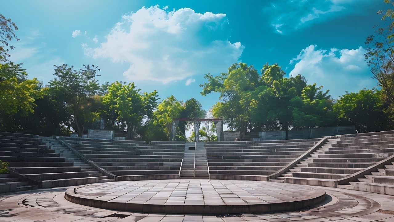 Open-air amphitheatre with tiered stone seating surrounded by landscaping